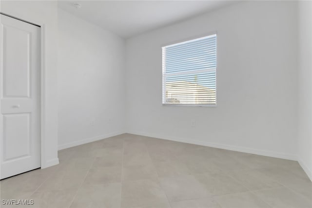 empty room with light tile patterned flooring and baseboards