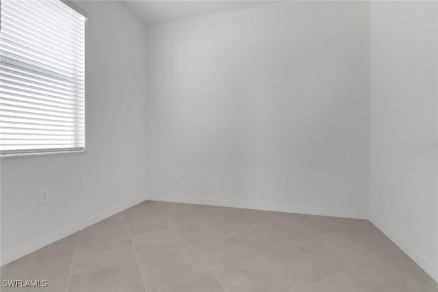 empty room with light tile patterned flooring and baseboards