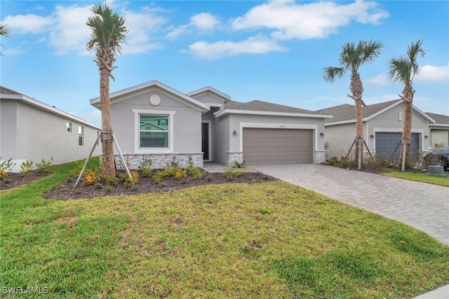 single story home featuring stone siding, a front lawn, decorative driveway, and an attached garage