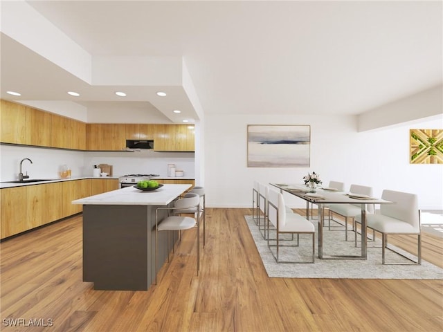 kitchen with range with gas stovetop, a center island, light countertops, a sink, and modern cabinets