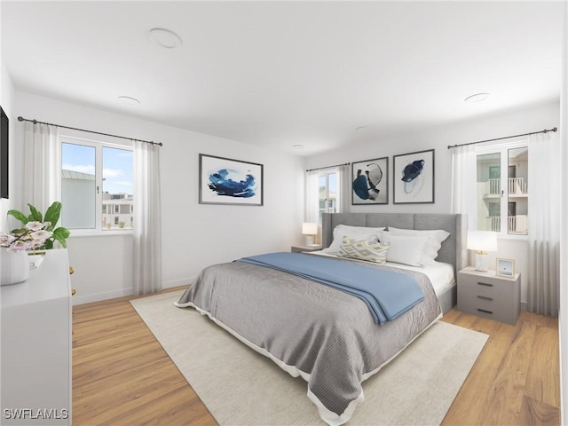 bedroom featuring light wood finished floors, multiple windows, and baseboards