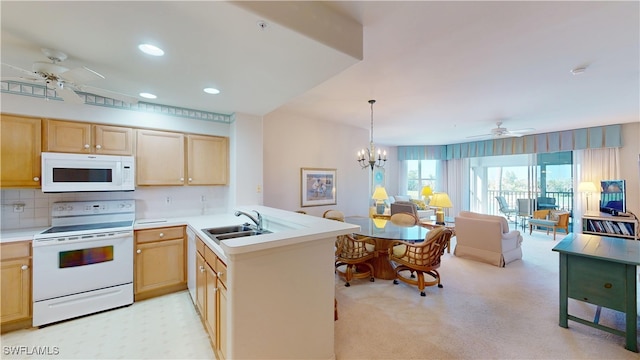 kitchen featuring open floor plan, a peninsula, white appliances, and a sink