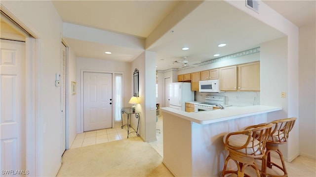 kitchen with a breakfast bar, recessed lighting, light countertops, visible vents, and white appliances