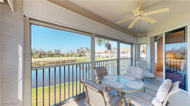 sunroom featuring a water view and ceiling fan