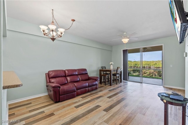 living room featuring baseboards, wood finished floors, and ceiling fan with notable chandelier