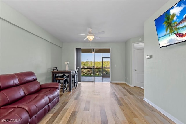 living area with light wood-style floors, ceiling fan, and baseboards