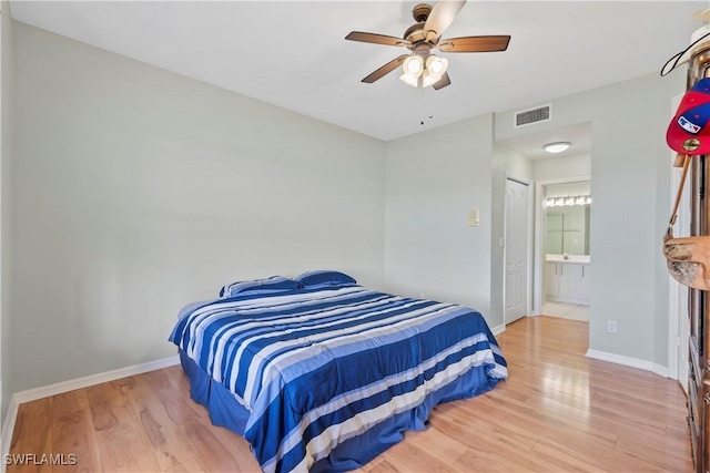 bedroom with visible vents, ensuite bathroom, baseboards, and wood finished floors