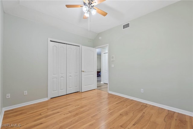 unfurnished bedroom with light wood-type flooring, baseboards, visible vents, and vaulted ceiling