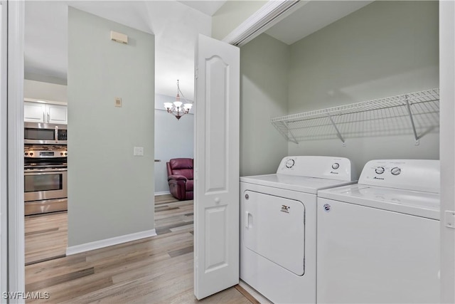 clothes washing area with a chandelier, laundry area, baseboards, light wood-style floors, and washer and dryer