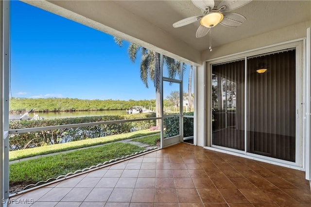 unfurnished sunroom featuring ceiling fan and a water view