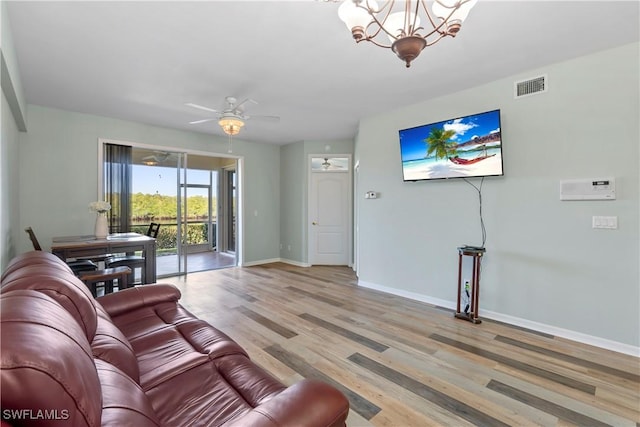 living room with ceiling fan with notable chandelier, light wood-type flooring, visible vents, and baseboards