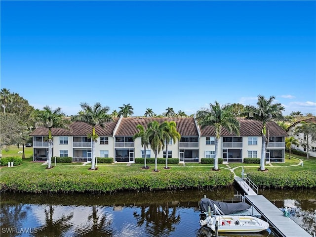 back of house featuring a water view, a tile roof, and a yard