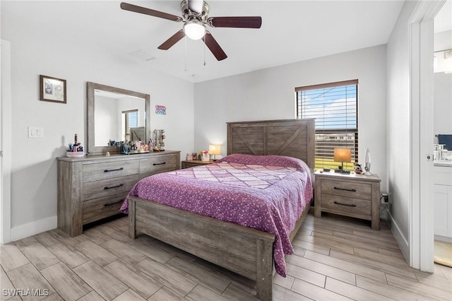 bedroom featuring a ceiling fan, wood finish floors, ensuite bath, and baseboards