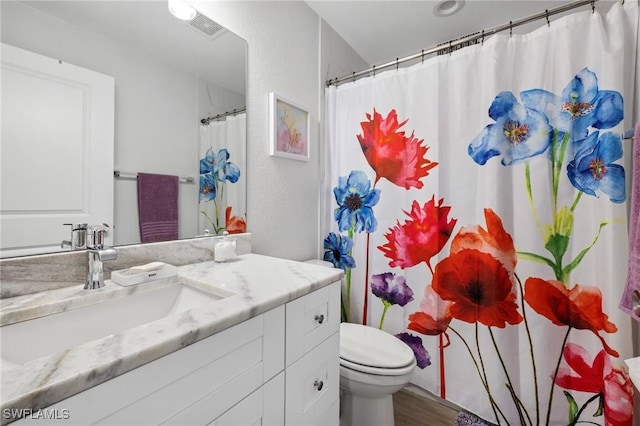 full bathroom featuring toilet, visible vents, wood finished floors, and vanity