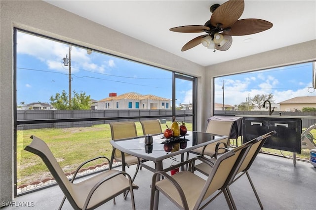 sunroom featuring a sink, a residential view, and a ceiling fan