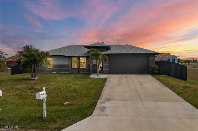 prairie-style house featuring a garage, concrete driveway, a yard, and fence