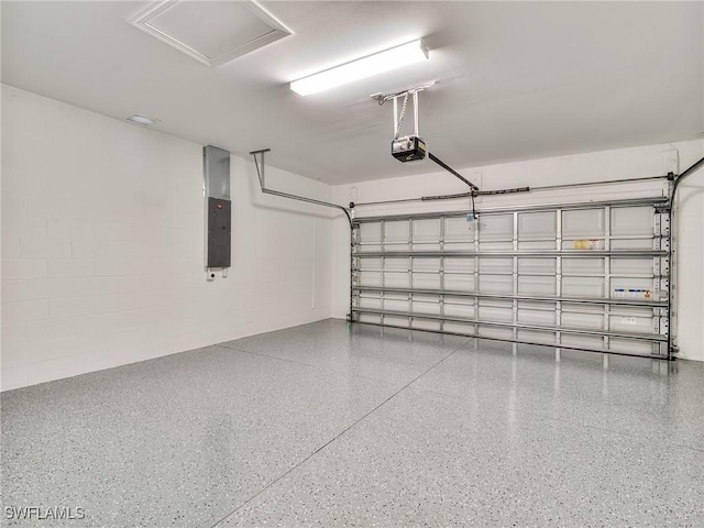 garage with concrete block wall, electric panel, and a garage door opener