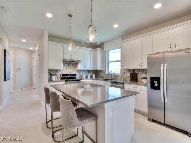 kitchen with white cabinets, under cabinet range hood, a kitchen island, and stainless steel appliances