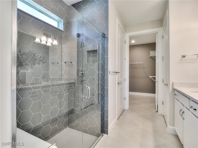 bathroom with vanity, baseboards, tile patterned floors, a stall shower, and a walk in closet