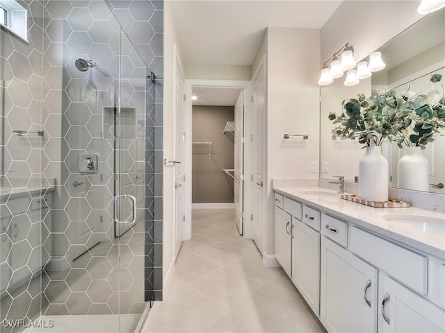 bathroom with double vanity, a stall shower, a walk in closet, and a sink