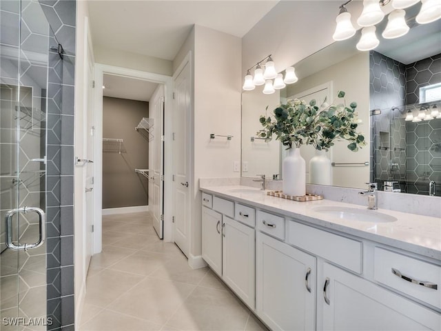 full bath with a stall shower, a sink, a walk in closet, and tile patterned floors