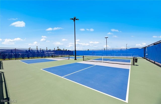 view of tennis court with community basketball court and fence