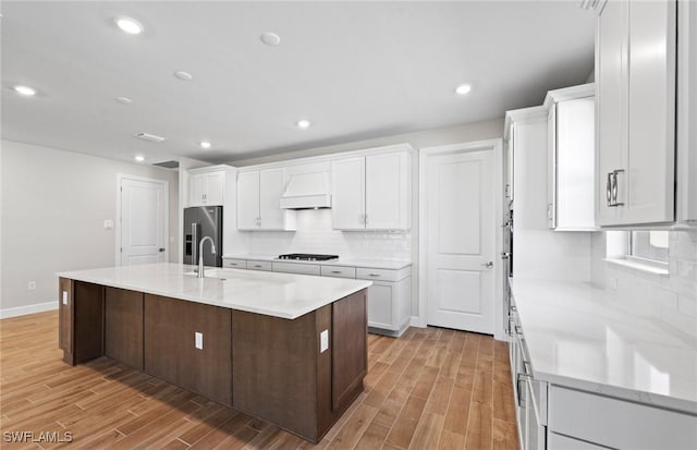 17333 Leaning Oak Trl, North Fort Myers, FL 33917 - kitchen with black stovetop, light wood finished floors, white cabinetry, high end fridge, and tasteful backsplash