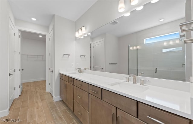 17333 Leaning Oak Trl, North Fort Myers, FL 33917 - full bathroom featuring a stall shower, double vanity, wood finished floors, a spacious closet, and recessed lighting