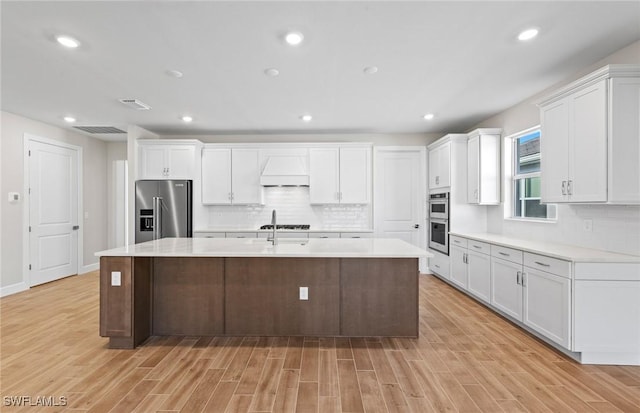 17333 Leaning Oak Trl, North Fort Myers, FL 33917 - kitchen featuring stainless steel appliances, light countertops, light wood-type flooring, custom range hood, and recessed lighting