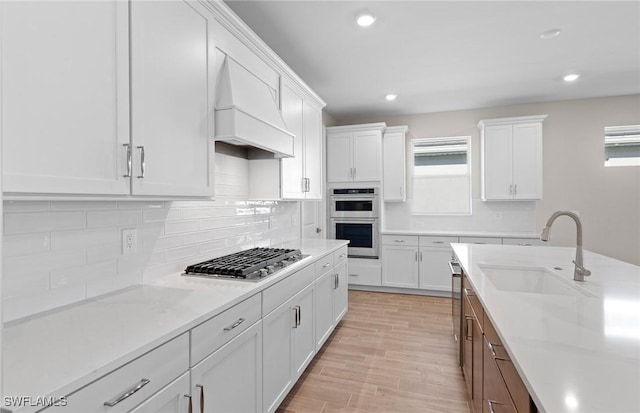 17333 Leaning Oak Trl, North Fort Myers, FL 33917 - kitchen featuring appliances with stainless steel finishes, custom range hood, white cabinetry, a sink, and light countertops