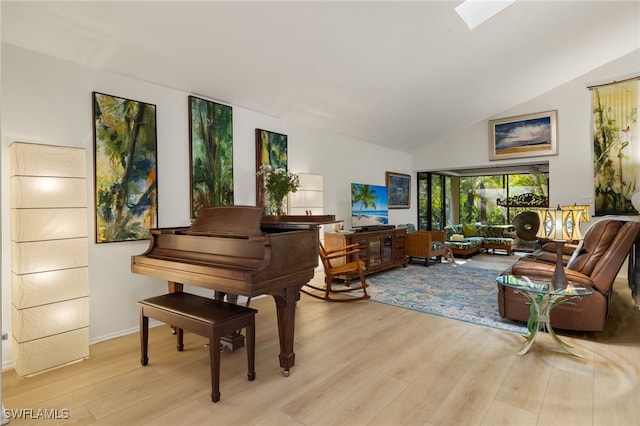 sitting room featuring a skylight, light wood-style flooring, high vaulted ceiling, and baseboards