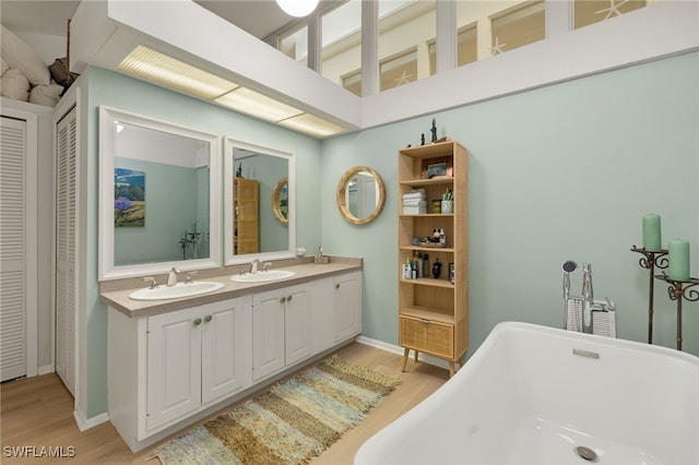 full bath featuring a soaking tub, a closet, a sink, and wood finished floors