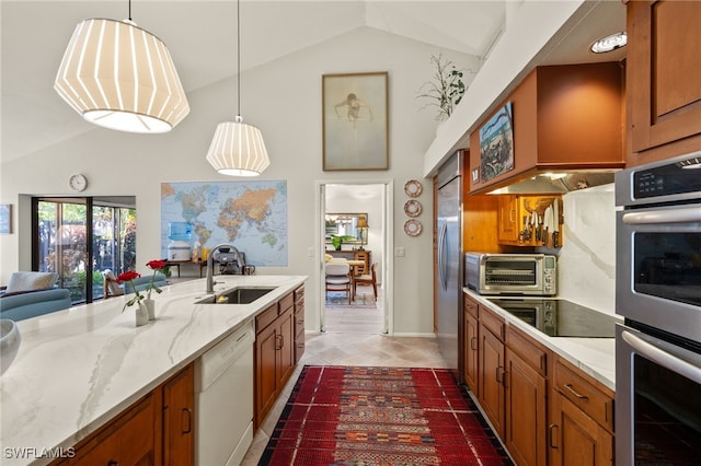 kitchen featuring hanging light fixtures, appliances with stainless steel finishes, brown cabinetry, and a sink