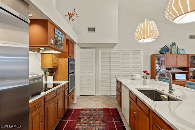 kitchen with stainless steel appliances, a sink, visible vents, brown cabinets, and decorative light fixtures