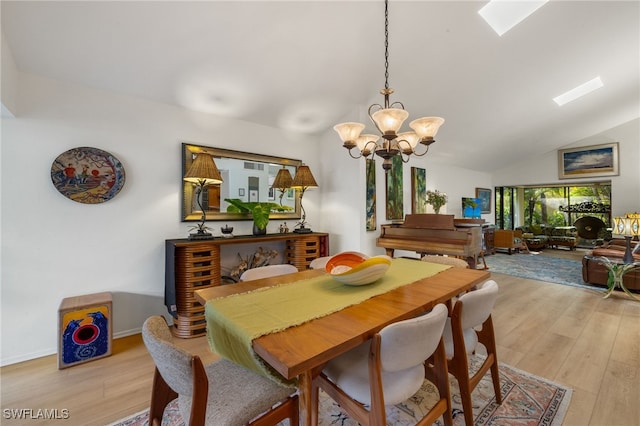 dining space with light wood-style floors, baseboards, lofted ceiling with skylight, and a notable chandelier