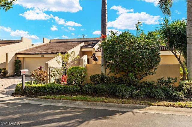 view of front of property with a garage, a tile roof, decorative driveway, and stucco siding