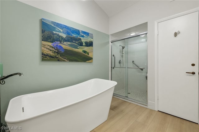 bathroom with a freestanding bath, a stall shower, and wood finished floors