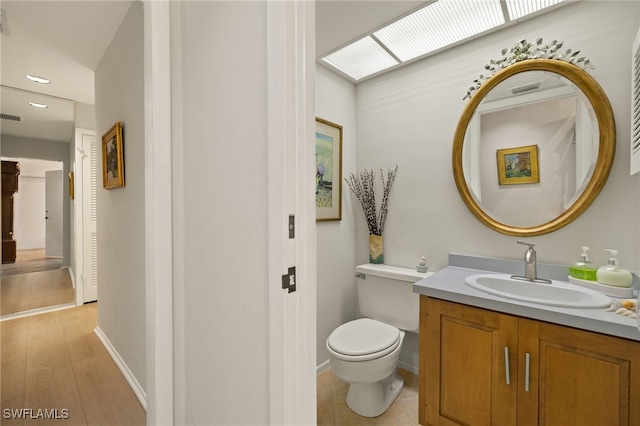 bathroom featuring a skylight, baseboards, vanity, and toilet