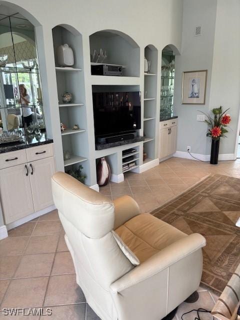 living room with visible vents, built in shelves, baseboards, arched walkways, and light tile patterned flooring