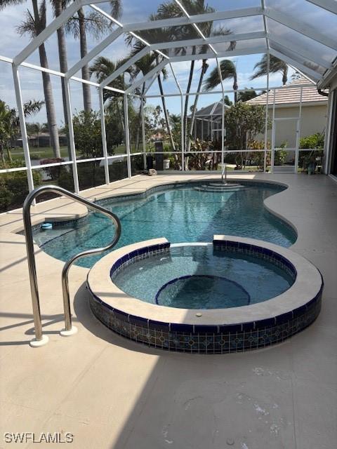 view of swimming pool with a lanai, a patio area, and a pool with connected hot tub