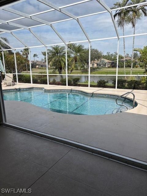 outdoor pool featuring glass enclosure and a patio