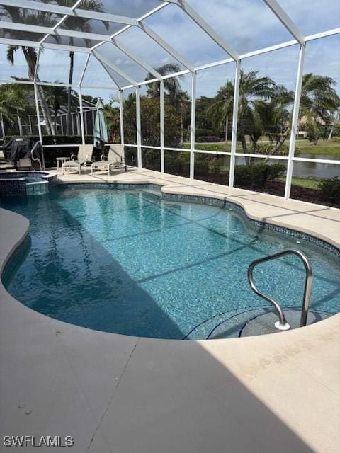 view of pool with glass enclosure, a pool with connected hot tub, and a patio area