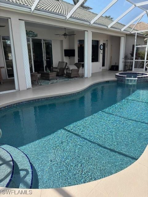 view of pool featuring glass enclosure, a ceiling fan, a pool with connected hot tub, a patio area, and an outdoor hangout area