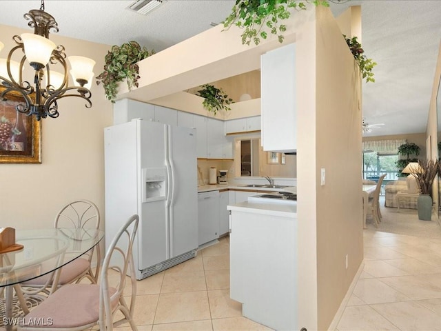 kitchen with light tile patterned floors, light countertops, visible vents, white cabinets, and white appliances