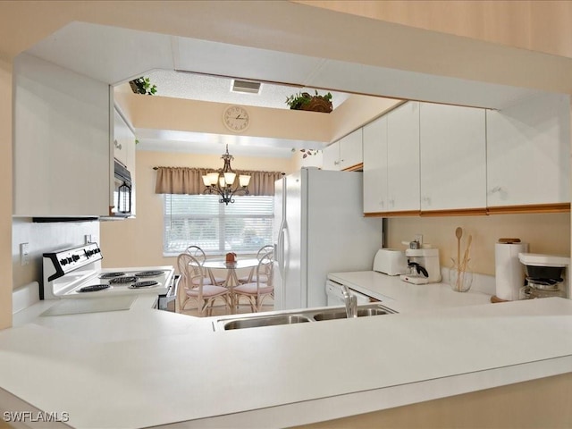 kitchen featuring pendant lighting, light countertops, white cabinets, a sink, and white appliances