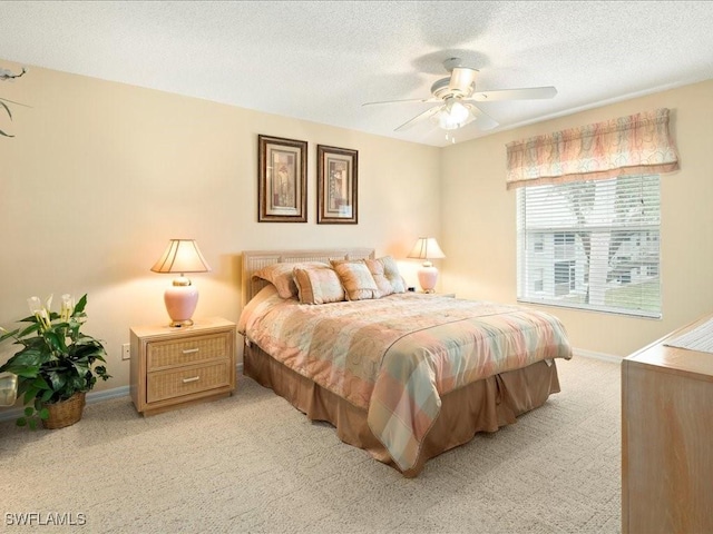 bedroom with a ceiling fan, light colored carpet, a textured ceiling, and baseboards