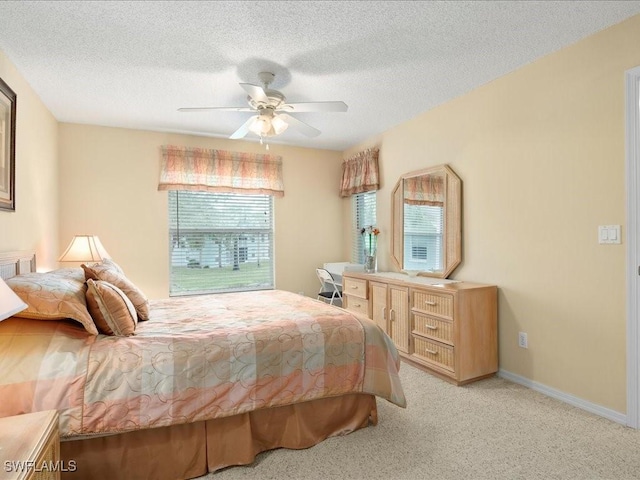 bedroom featuring light carpet, a ceiling fan, baseboards, and a textured ceiling