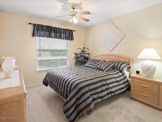 bedroom with a ceiling fan, light carpet, and baseboards