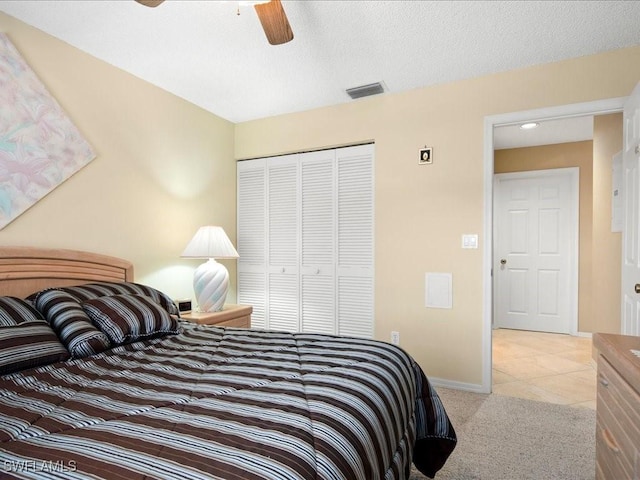 bedroom with ceiling fan, light colored carpet, visible vents, baseboards, and a closet