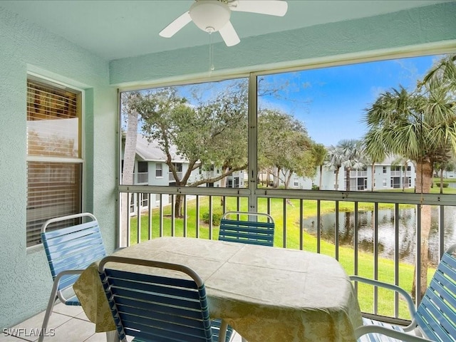 sunroom / solarium featuring a water view and ceiling fan